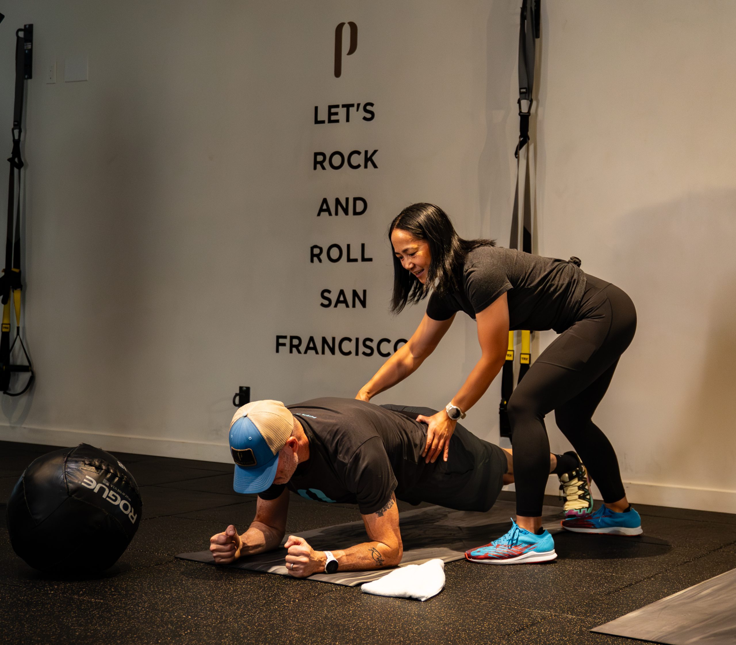 Coach guiding an athlete through a push-up on the training floor