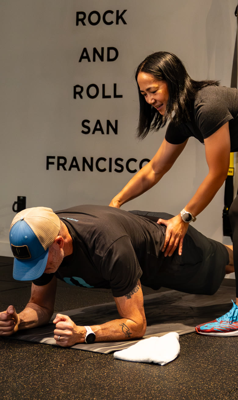 Coach adjusting an athlete’s plank on the strength floor