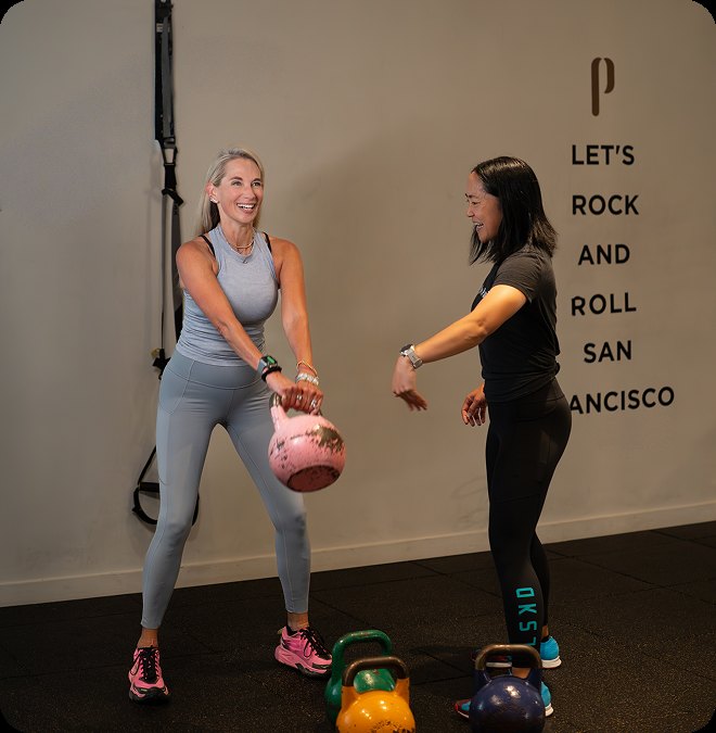 A coach and member training with kettlebells